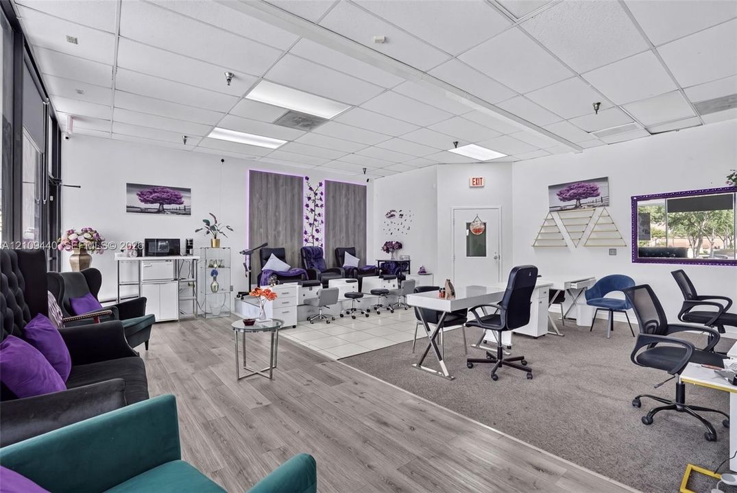 Open-concept commercial space featuring drop ceiling with recessed lighting, wood-finish flooring, tiled platform area, and neutral wall tones