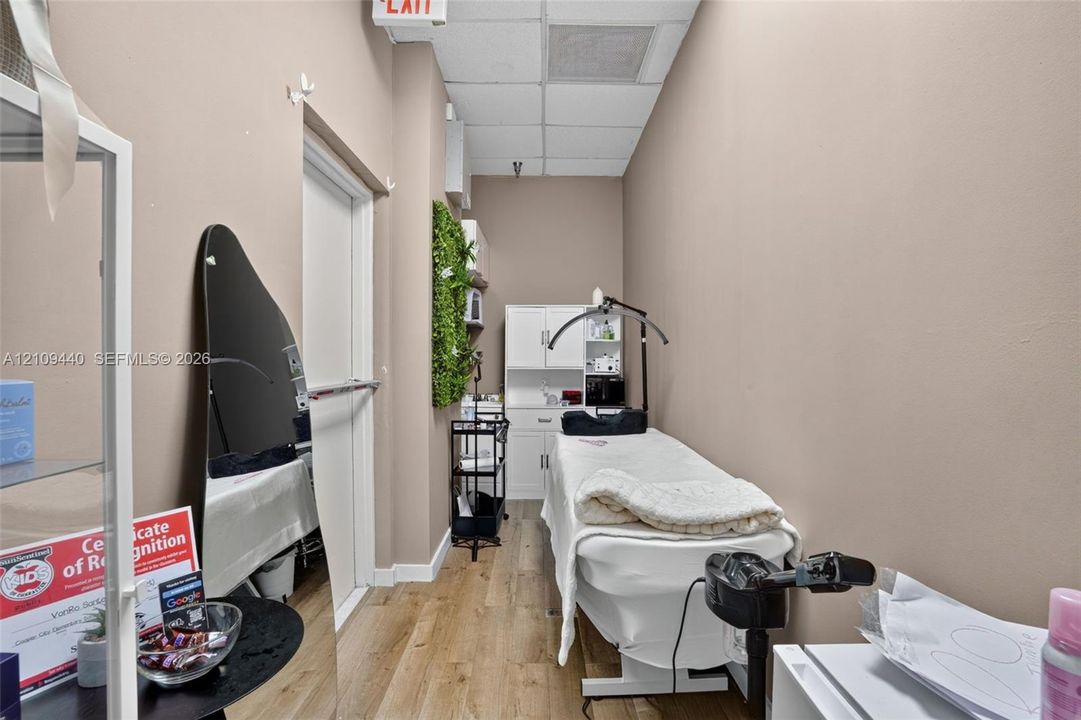 Enclosed interior space featuring wood-finish flooring, white built-in cabinetry, and a drop ceiling
