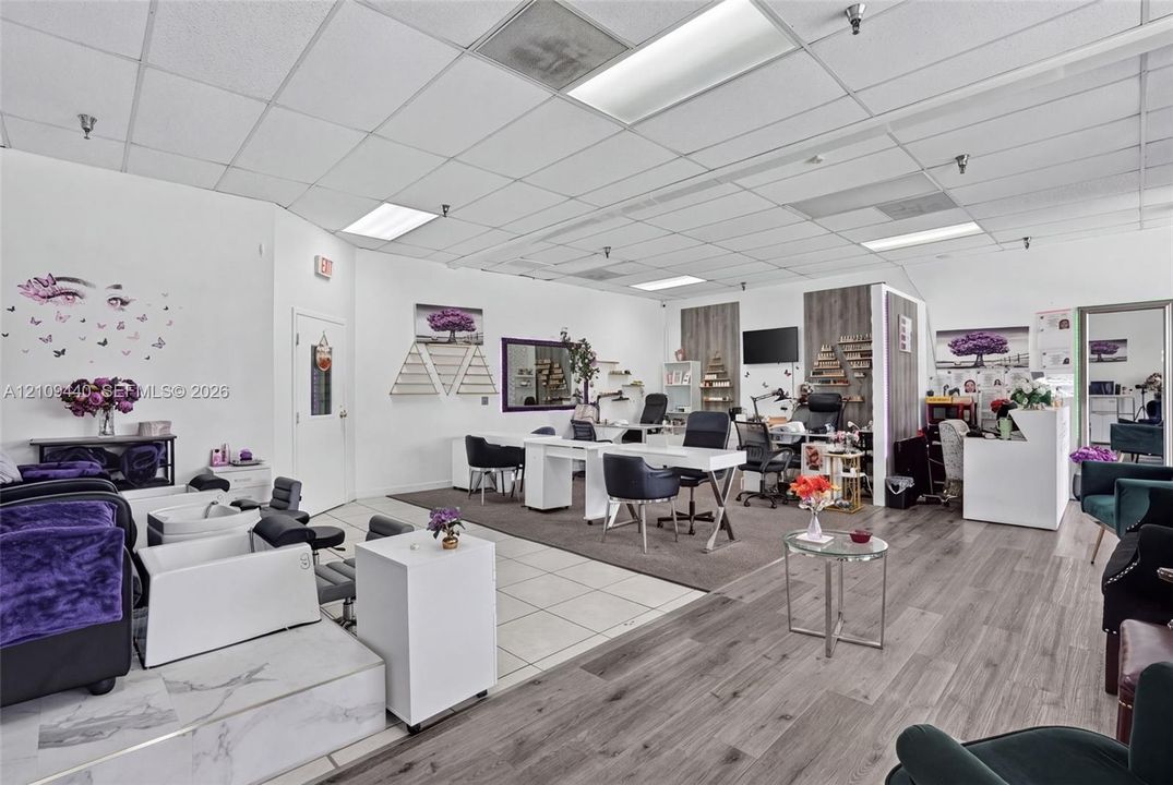 Commercial space featuring a drop ceiling with recessed lighting, integrated wood-finish flooring, tiled platform area, and neutral wall surfaces