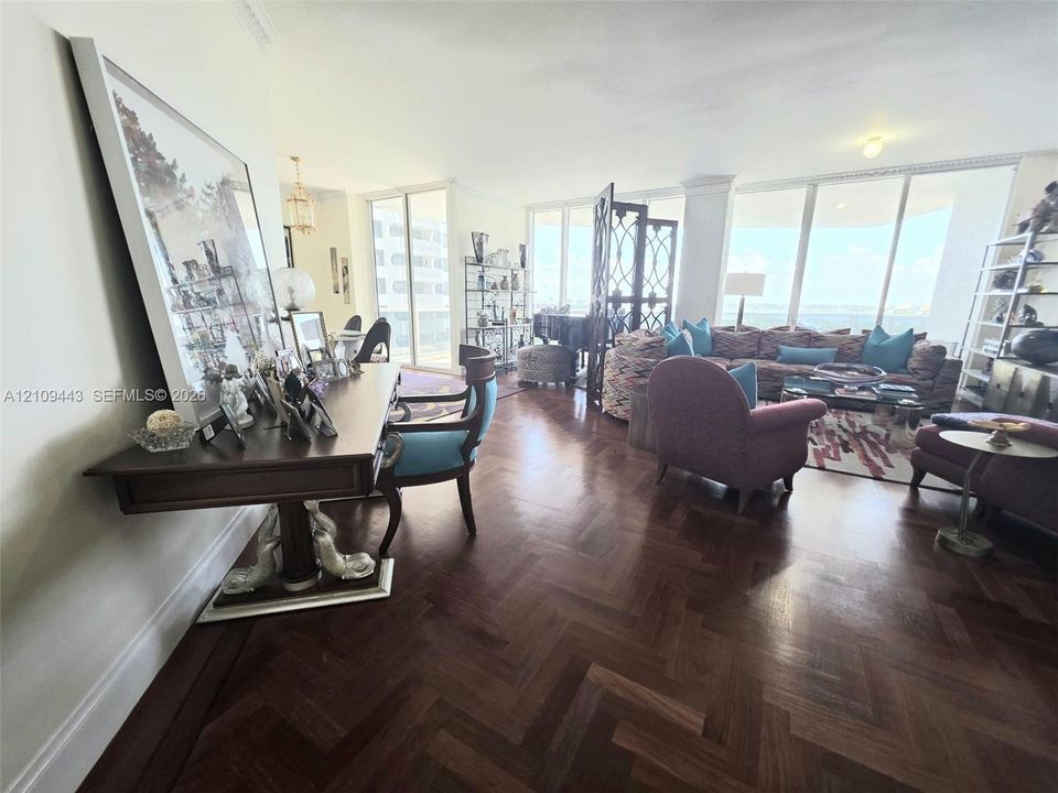 Herringbone-patterned wood-finish flooring, floor-to-ceiling windows, and crown molding