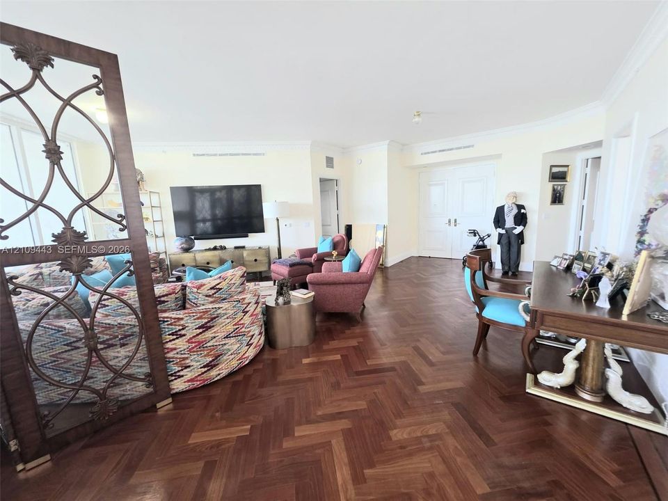 Herringbone-patterned wood-finish flooring, decorative metal room divider, and double-door entry
