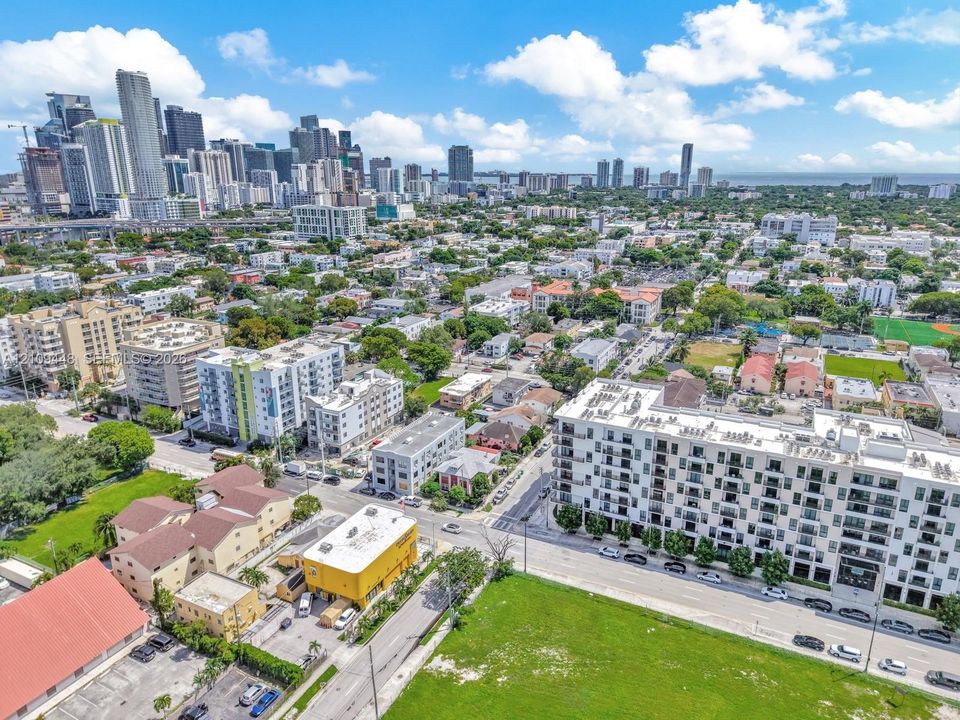Aerial perspective of the urban landscape featuring multi-story residential buildings, paved street grids, and proximity to the city skyline