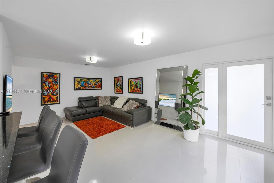 Open-concept interior featuring polished tile flooring, recessed ceiling lighting, and a glass-paneled entry door