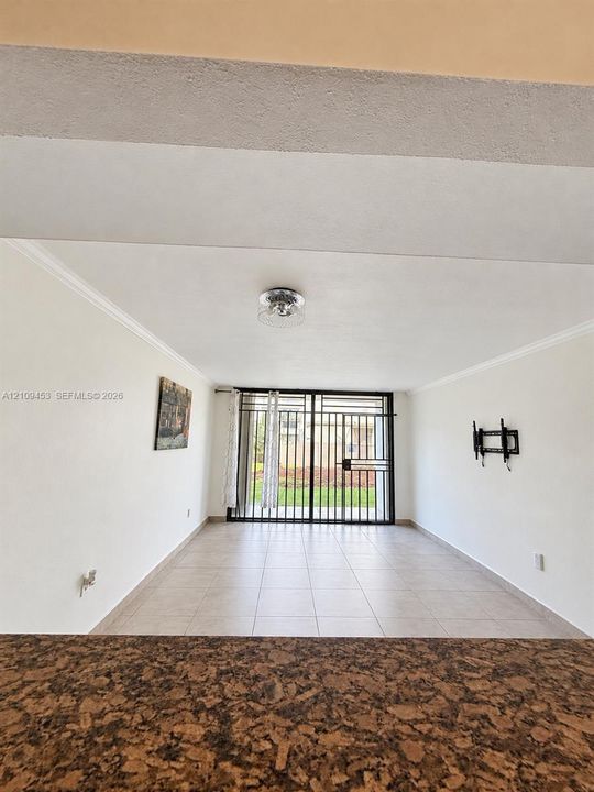 Interior area featuring tile flooring, crown molding, a central flush-mount ceiling light, and a metal security screen door