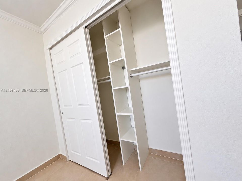 Closet featuring white six-panel sliding doors, built-in vertical shelving, overhead storage shelf, and horizontal hanging rod