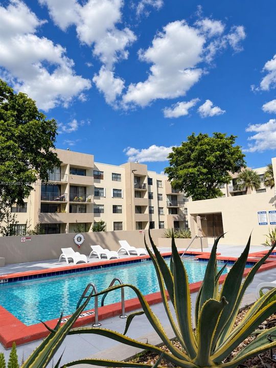Swimming pool featuring a terra-cotta tiled perimeter, metal handrails, and concrete decking