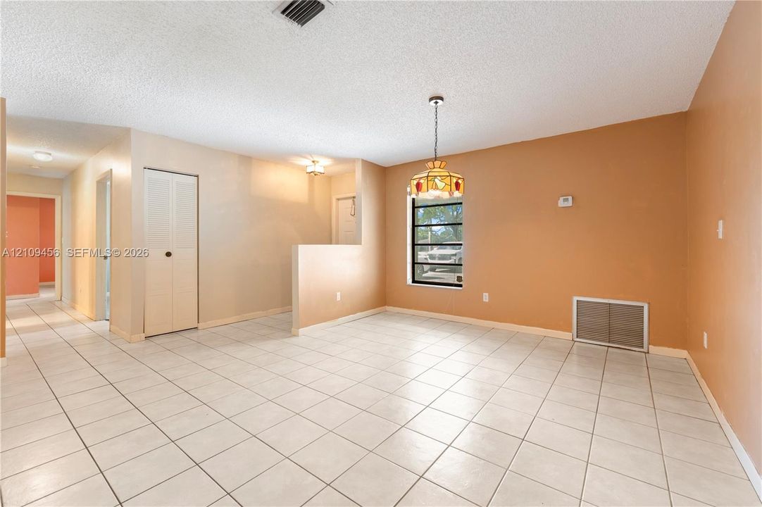 Neutral-toned ceramic tile flooring, built-in closet with biforced doors, decorative stained-glass pendant lighting, and a low-profile partition wall