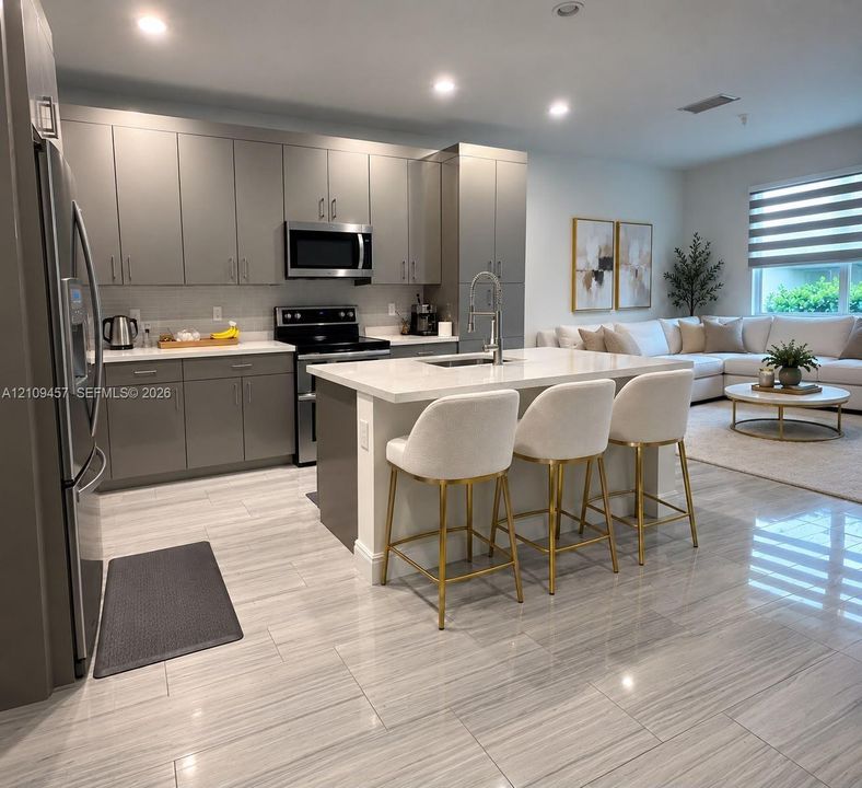 Kitchen featuring high-gloss cabinetry, stone-finish countertops, stainless steel appliances, a center island with bar seating, and large-format tile flooring