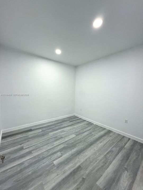 Room featuring neutral walls and wood-finish flooring with recessed lighting