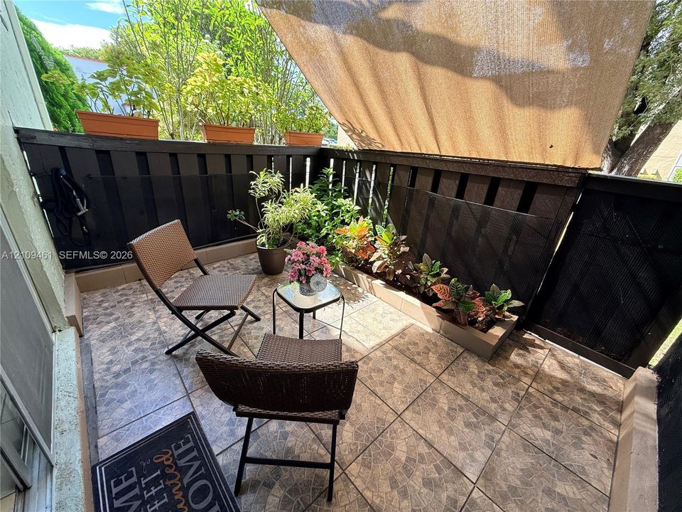 Private balcony featuring tiled flooring, built-in wooden perimeter privacy fencing, and a retractable fabric awning