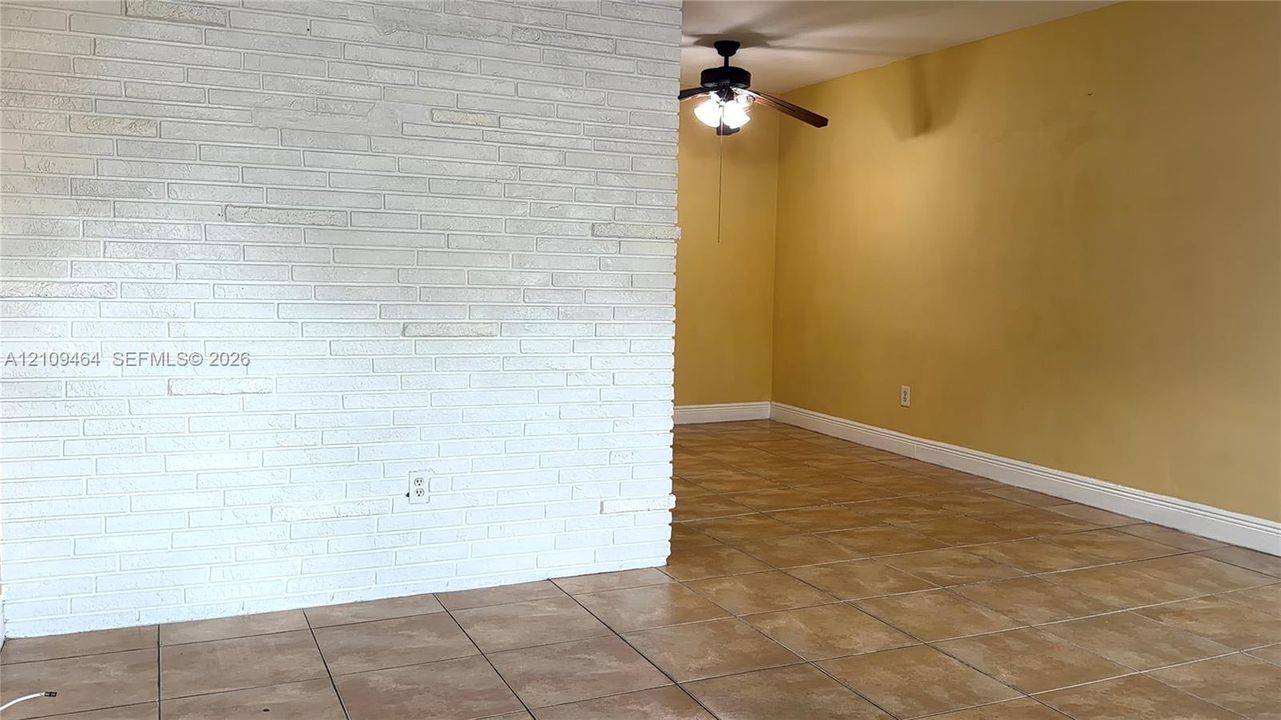 White painted masonry accent wall, neutral ceramic tile flooring, and ceiling-mounted light fixture