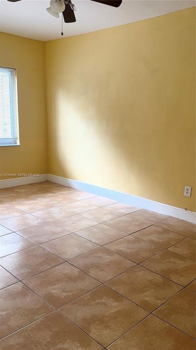 Room featuring large-format tile flooring and a ceiling-mounted light fixture with a fan