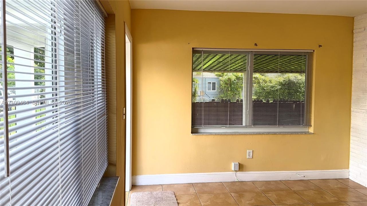 Interior space featuring large rectangular windows, tiled flooring, and white-painted brick accents