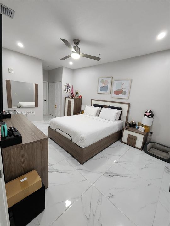 Large-format tile flooring with marble-style veining, recessed lighting, and a modern ceiling fan with integrated illumination