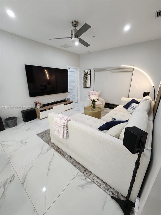 Large-format stone-style flooring with veining, recessed lighting, and a modern multi-blade ceiling fan