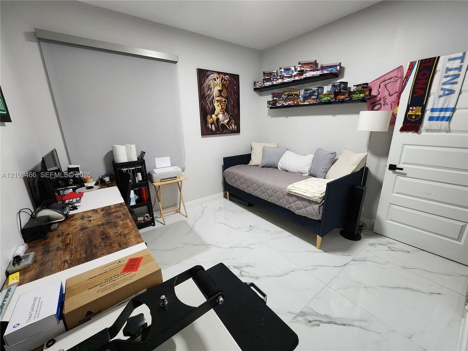 Large-format tile flooring, neutral wall tones, and a multi-panel interior door with matte black hardware