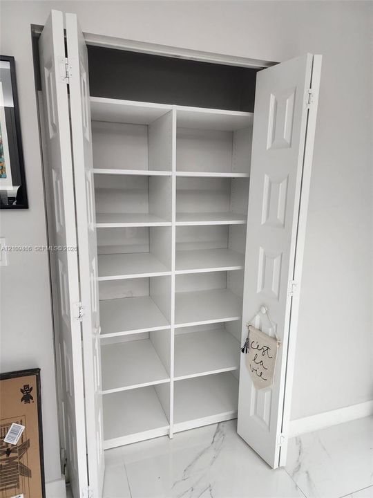 Built-in closet featuring white paneled bi-fold doors, adjustable shelving, and a vertical center divider
