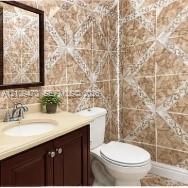 Vanity featuring a solid-surface countertop with an integrated oval basin and dark wood-finish cabinetry, complemented by decorative geometric wall tile and a framed wall mirror