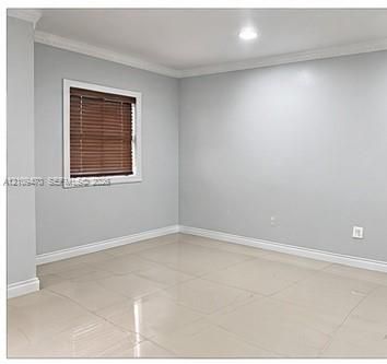 Neutral-toned interior space featuring light-colored tile flooring, crown molding, and recessed lighting