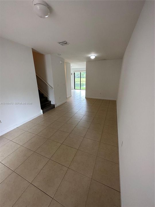 Neutral-toned ceramic tile flooring, staircase with a handrail, flush-mount ceiling lighting, and sliding glass door