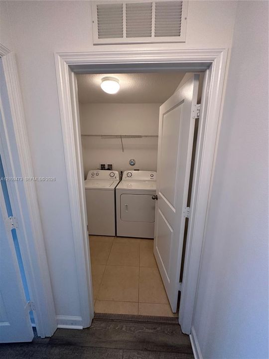 Dedicated laundry area featuring ceramic tile flooring, a recessed ceiling light fixture, and a wire shelving system