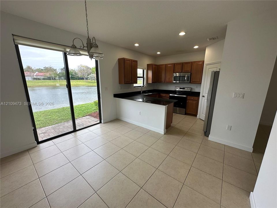 Kitchen featuring wood cabinetry, stone countertops, stainless steel appliances, tile flooring, and sliding glass doors with water exposure