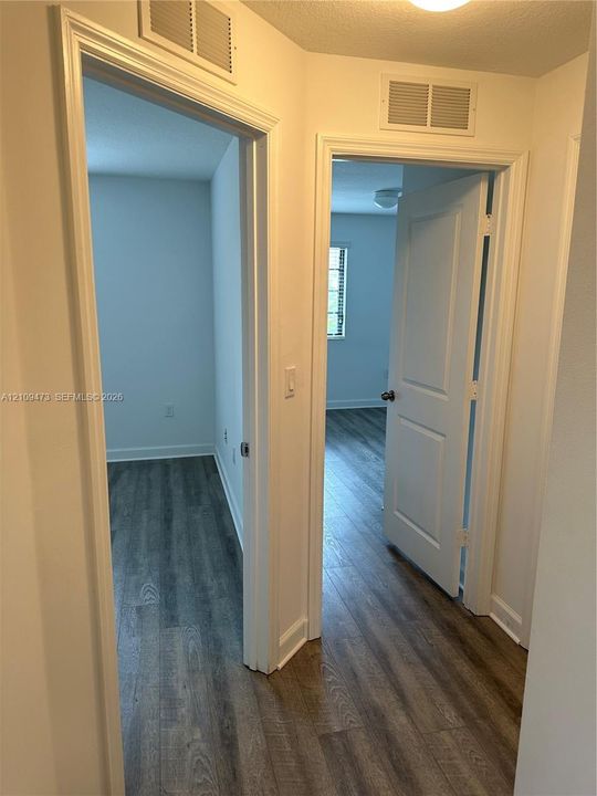 Interior hallway featuring wood-finish flooring, two-panel interior doors, and crisp white casing