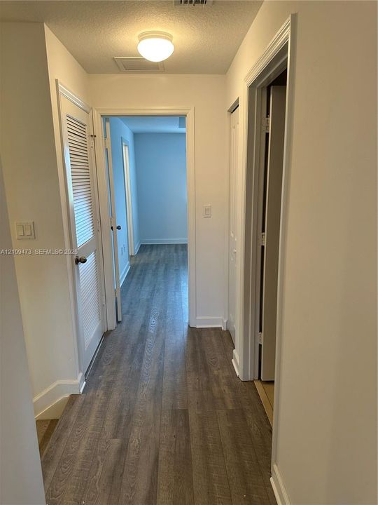 Hallway featuring wood-finish flooring, a louvered closet door, and a flush-mount ceiling light fixture
