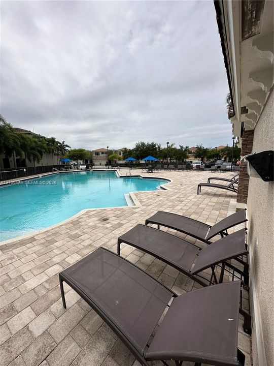 In-ground swimming pool featuring a paver stone deck and stone-clad exterior wall