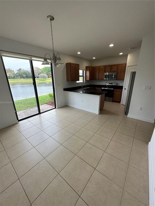 Kitchen featuring dark-toned cabinetry, a peninsula, stainless steel appliances, tile flooring, and sliding glass doors with water scenery