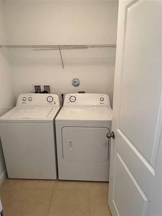 Laundry area featuring tile flooring, white panel door, and overhead wire shelving