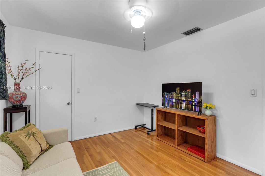 Room featuring wood-finish flooring and a central ceiling fan with integrated lighting