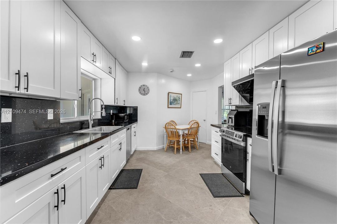 Kitchen featuring white shaker-style cabinetry, contrasting dark countertops, tile flooring, recessed lighting, and stainless steel appliances