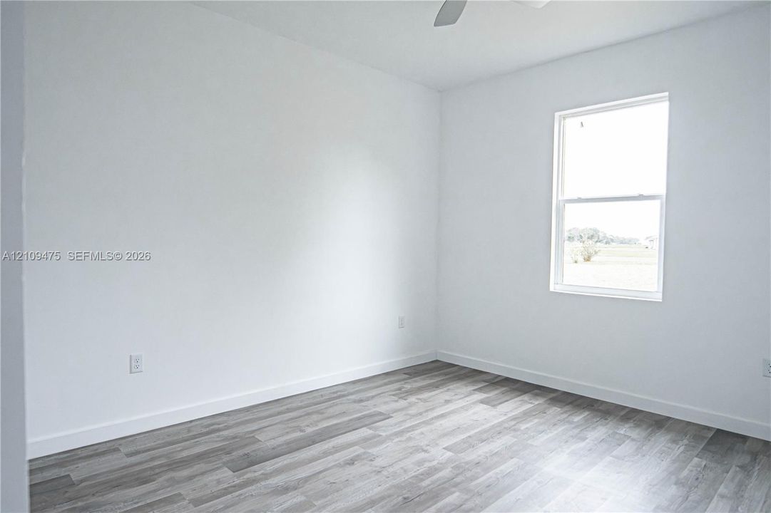 Room with neutral walls, wood-finish flooring, single-hung window, and overhead ceiling fan