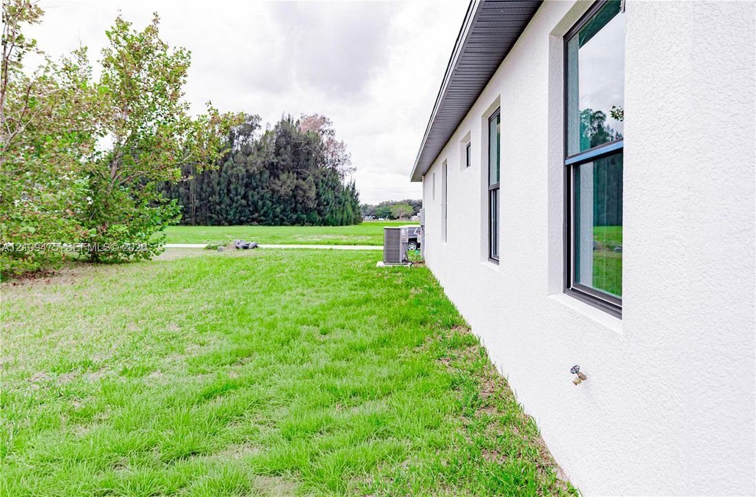 Stucco exterior, expansive lawn, and window frames with dark trim