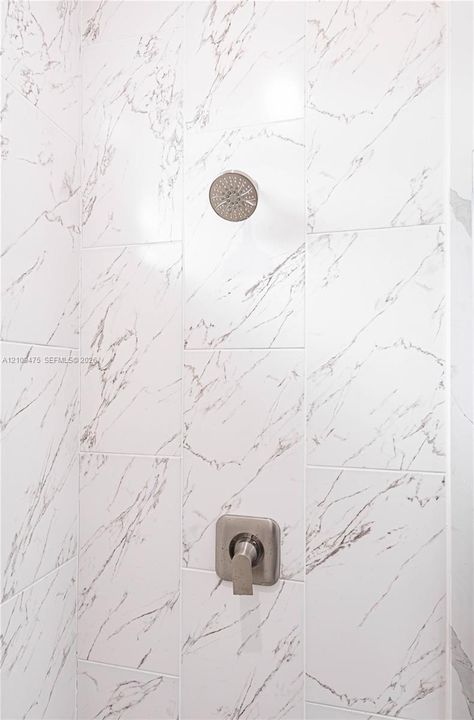 Shower enclosure featuring large-format veined tile walls, a brushed nickel rainfall showerhead, and a matching single-handle pressure-balance valve