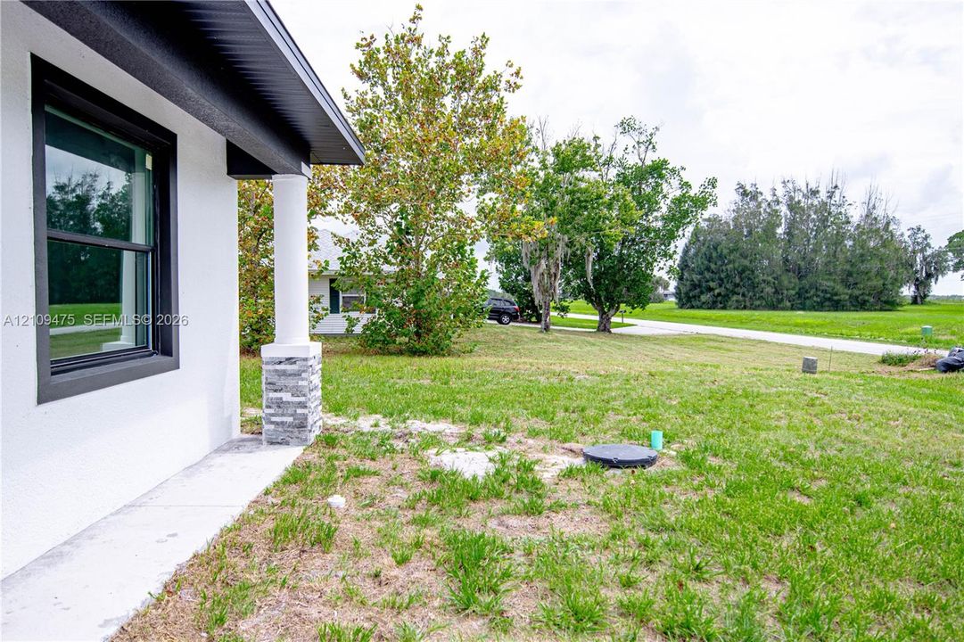 Exterior elevation featuring white stucco siding, a concrete porch, and a column with stacked stone base detailing