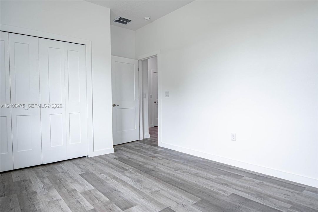 Interior room featuring wood-finish flooring, two-panel interior doors, and a double-door closet