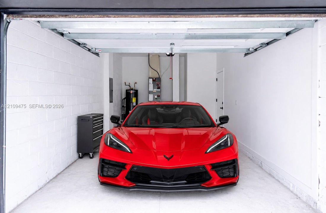 Enclosed garage featuring painted concrete block walls, overhead sectional door, and dedicated utility area
