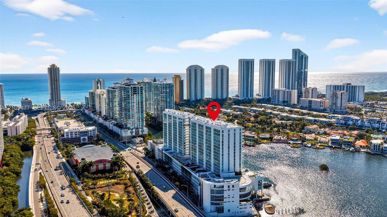 High-rise residential building featuring a swimming pool, tennis court, and immediate proximity to waterfront areas