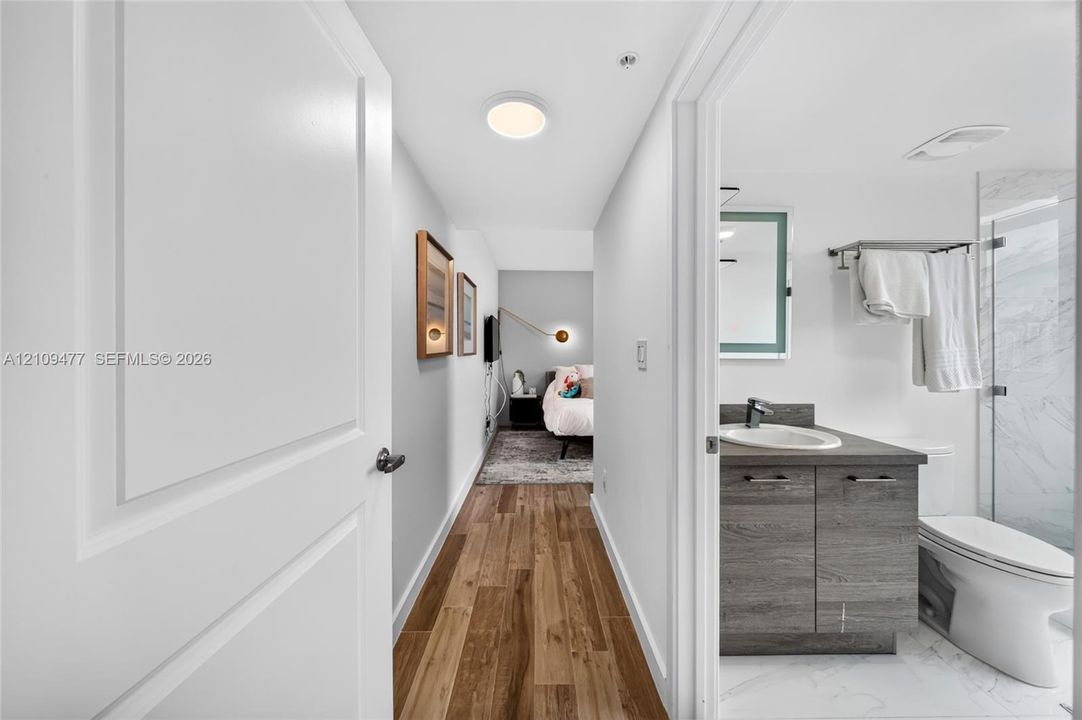 Private balcony featuring wood-finish tile flooring, a glass-panel railing, and frosted privacy partitions