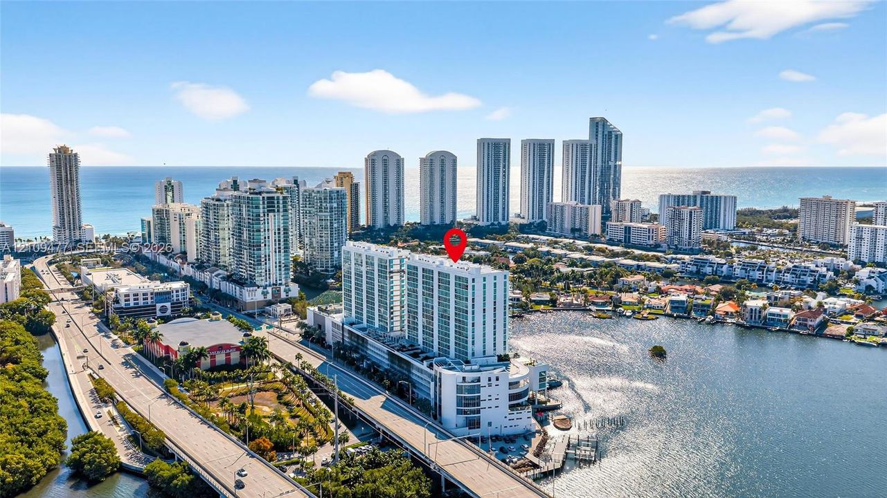 High-rise coastal property featuring deep-water marina slips, rooftop tennis court, expansive glass-paneled balconies, and manicured terrace landscaping