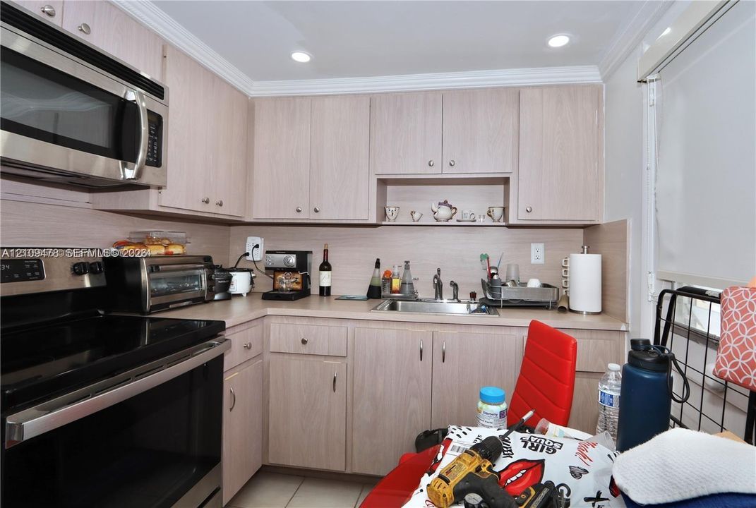 Kitchen featuring light-finish cabinetry, stainless steel appliances including an over-the-range microwave and electric range, and integrated under-cabinet lighting