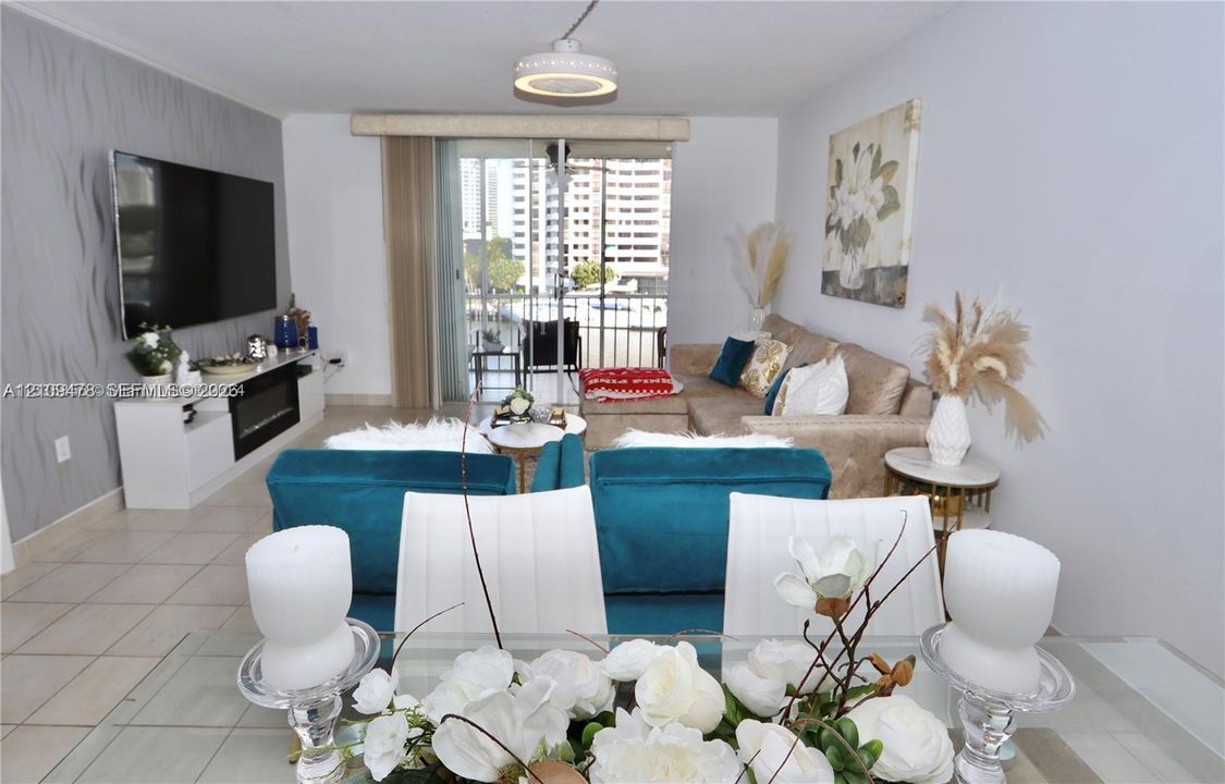 Living area featuring tile flooring, a built-in media console with an integrated fireplace, textured accent wall, flush-mount ceiling lighting, and sliding glass doors