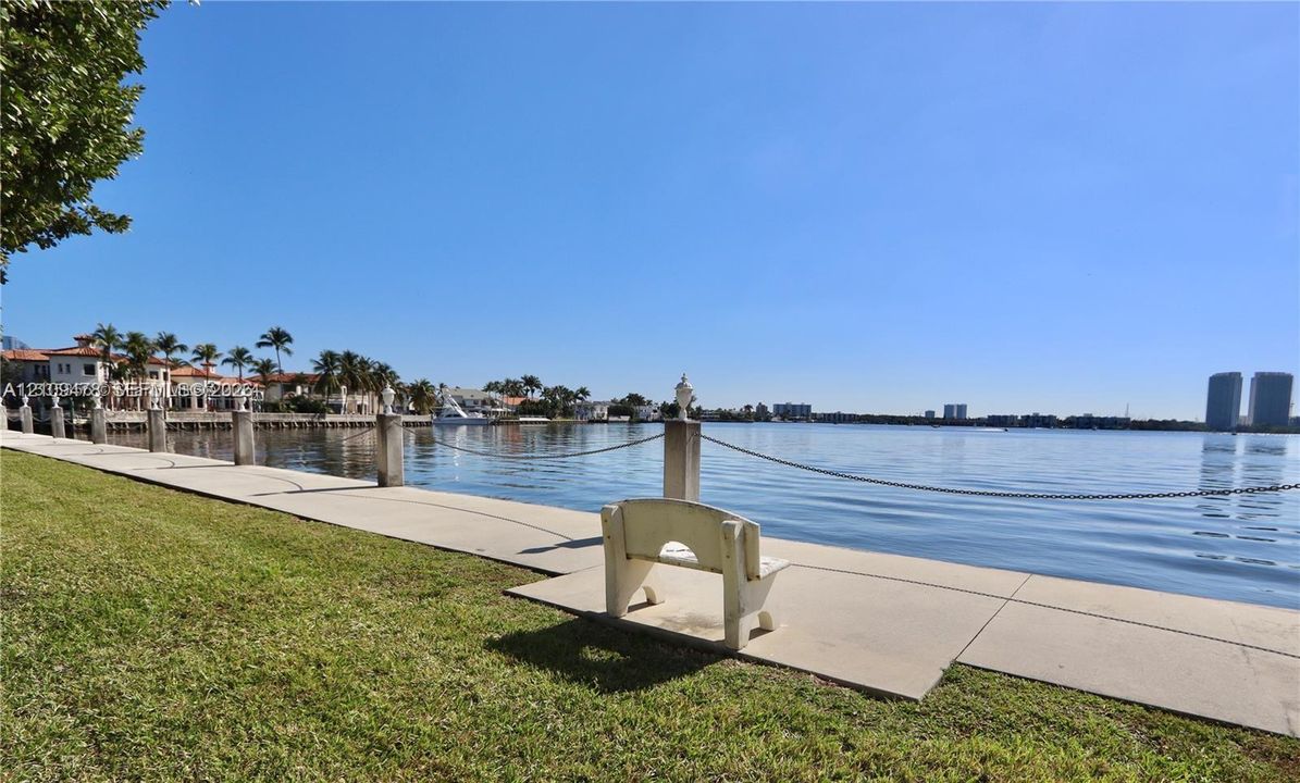 Waterfront property featuring a concrete seawall, decorative stone capped posts with chain railings, and a landscaped lawn