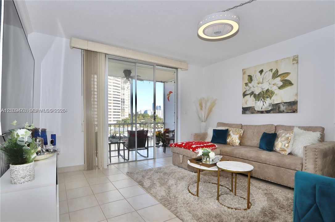 Living space featuring neutral ceramic tile flooring, circular contemporary ceiling light fixture, and sliding glass doors with vertical blinds