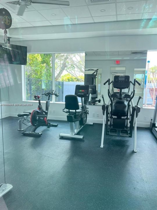 Fitness center featuring rubber flooring, floor-to-ceiling mirror, expansive windows, and recessed ceiling lighting