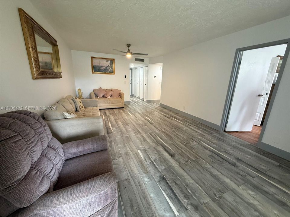 Living area featuring wood-finish flooring, recessed ceiling lighting, and a ceiling fan
