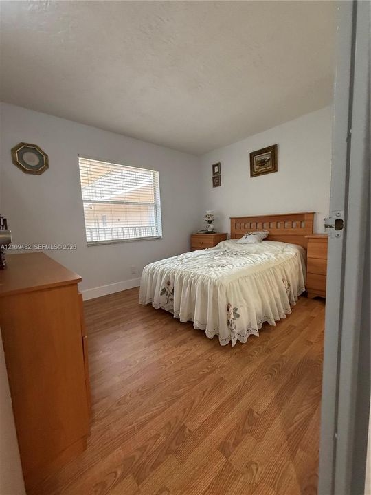 Wood-finish flooring and a single-pane window with horizontal blinds