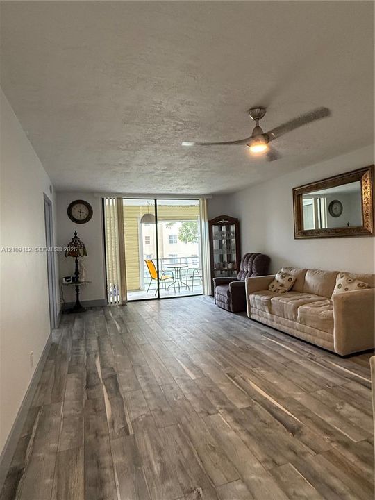 Interior space featuring wood-finish flooring, a contemporary ceiling fan with integrated lighting, and glass sliding doors providing external exposure